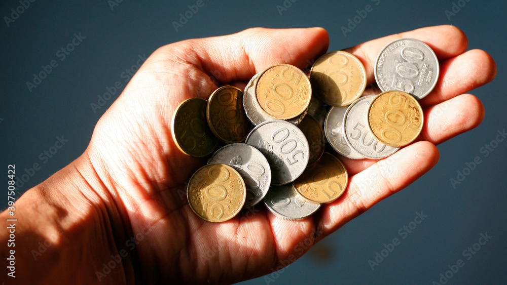 hand holding indonesia currency coins on a blue background hand holding indonesia currency coins on a blue background