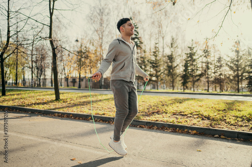 athlete male Caucasian appearance engaged in training on the street portrait, jumping rope for a long time. sports cardio warm-up before active fitness on the autumn street.