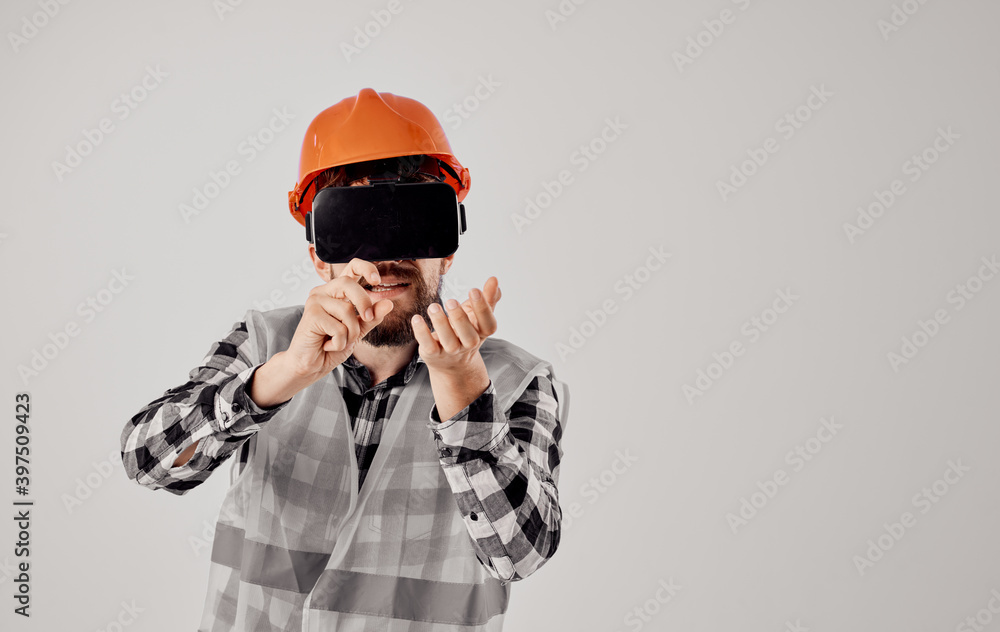 a builder in an orange helmet and 3D glasses gestures with his hands Copy Space light background a builder in an orange helmet and 3D glasses gestures with his hands Copy Space light background