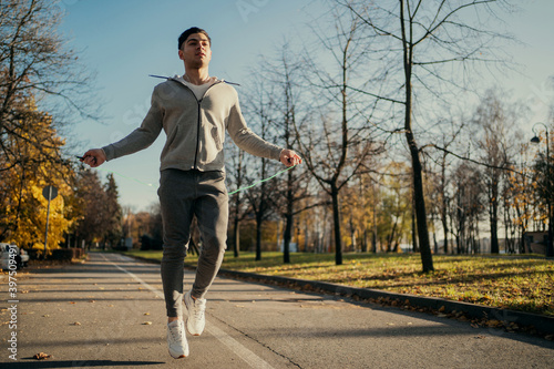 sports cardio warm-up before active fitness on the autumn street. a male athlete of Caucasian appearance is engaged in training on the street, jumping rope for a long time.