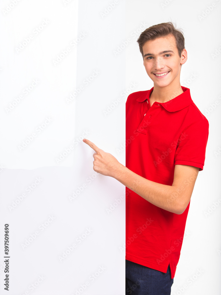 Photo of smiling Handsome white guy pointing on advertising big board. Portrait of happy young man pointing buy finger to the white banner, isolated over white background. Advertise concept. Photo of smiling Handsome white guy pointing on advertising big board. Portrait of happy young man pointing buy finger to the white banner, isolated over white background. Advertise concept.