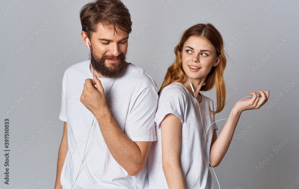 happy man and woman in headphones on gray background look and stand with their backs to each other happy man and woman in headphones on gray background look and stand with their backs to each other