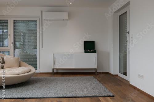 Wohnzimmer mit Plattenspieler am Regal, rundem Sofa und Holzfußboden. 