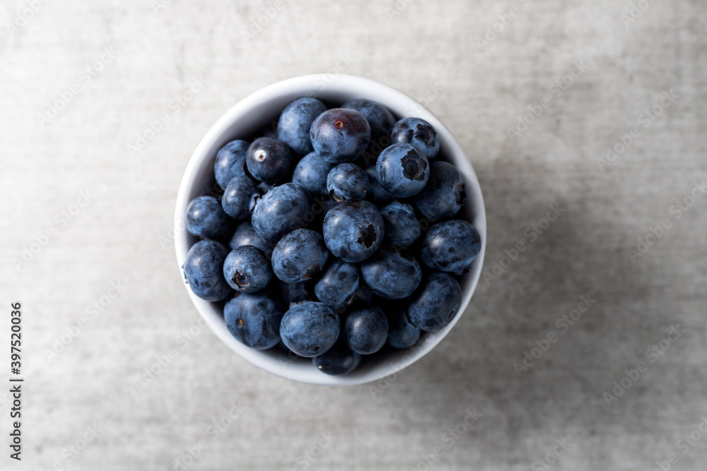 Lot of fresh delicious blueberries on a white pot over a wooden table Lot of fresh delicious blueberries on a white pot over a wooden table