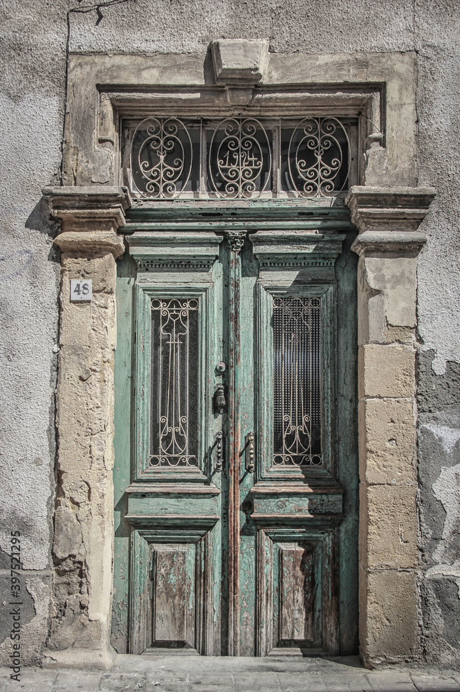 Old Medittaranean door in Cyprus with peeling paint but remnants of grandeur.