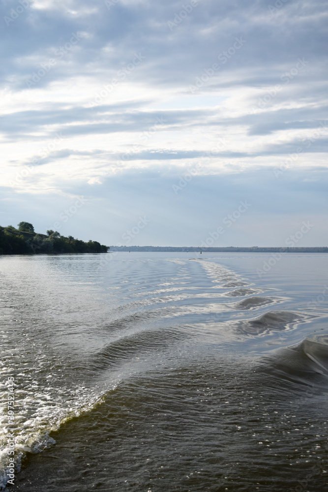 Fototapeta premium diverging waves of the wake on the background of the sunset coast