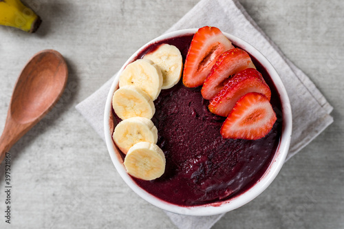 Brazilian frozen açai berry ice cream bowl with strawberries and bananas. with fruits on wooden background. Summer menu top view. close up photo