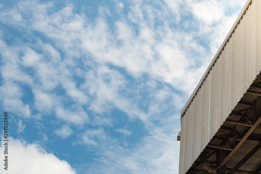 Low angle view edge of metal sheet roof outside the building against blue sky and white clouds background. Low angle view edge of metal sheet roof outside the building against blue sky and white clouds background.