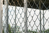 Selective focus Chain Link fence against blurred inside roof structure, building and sky background.