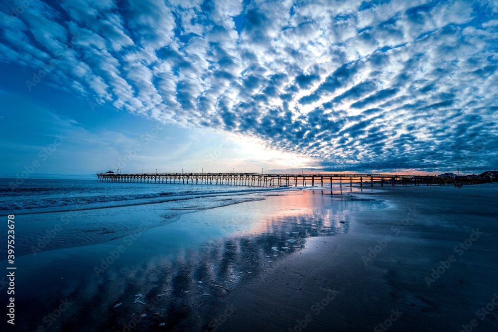 An ocean pier with dramatic clouds over the sea after sunset.