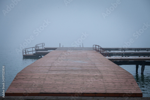 Fototapeta Naklejka Na Ścianę i Meble -  Pontoon on the Palic lake near Subotica, Serbia, with grey waters in autumn and a heavy and mysterious smoggy fog and mist