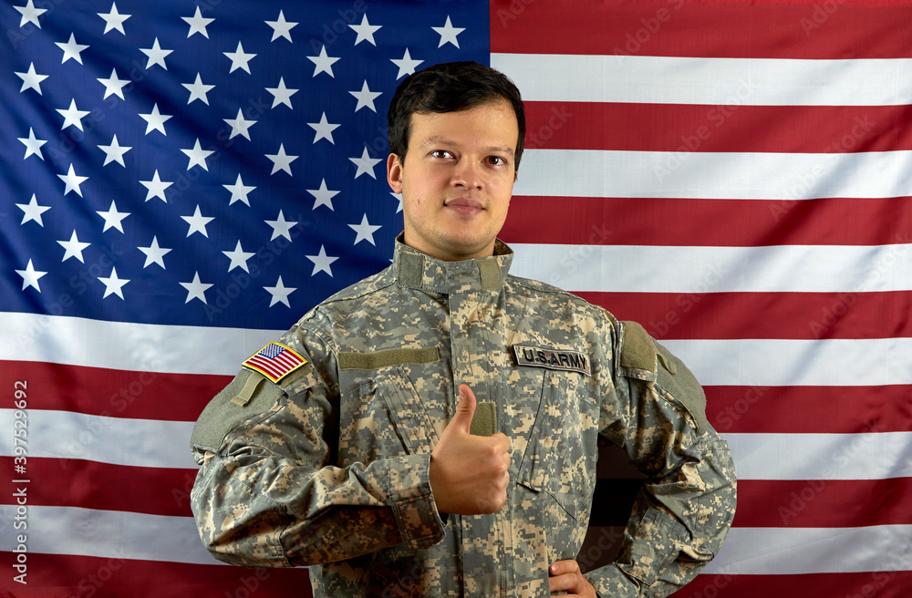 American army soldier on the background of the American flag. Portrait of a US Soldier showing a class gesture. The concept of patriotism American army soldier on the background of the American flag. Portrait of a US Soldier showing a class gesture. The concept of patriotism