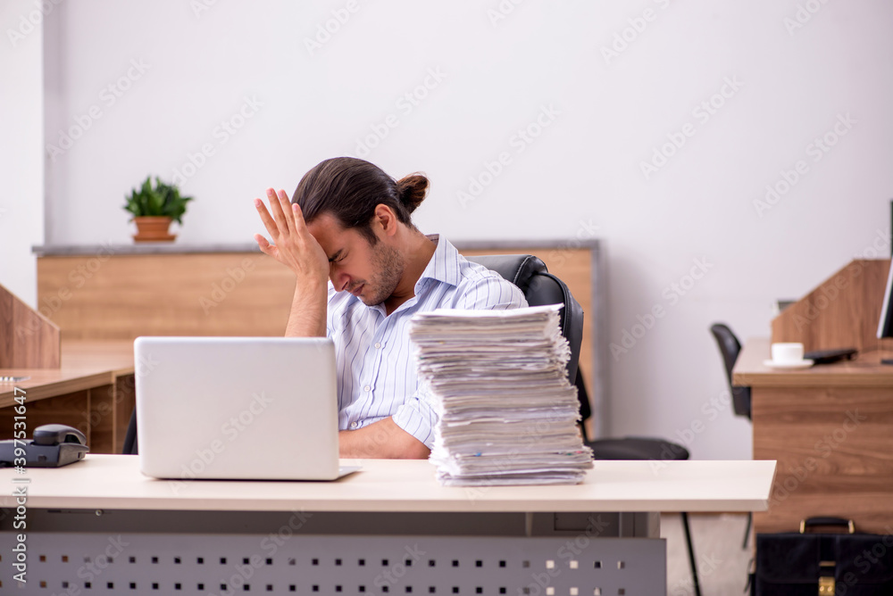 Young male employee unhappy with excessive work Young male employee unhappy with excessive work