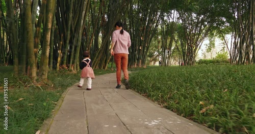 Happy little asian baby girl walking with her mother in the bamboo garden outdoor in Chengdu Wangjiang park Chinese woman with her daughter lifestyles 4k footage photo