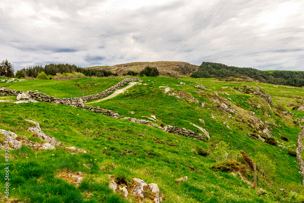 Green slopes of Mosteroy island with Mastravarden hill in a distance, Rennesoy kommune, Stavanger, Norway, May 2018