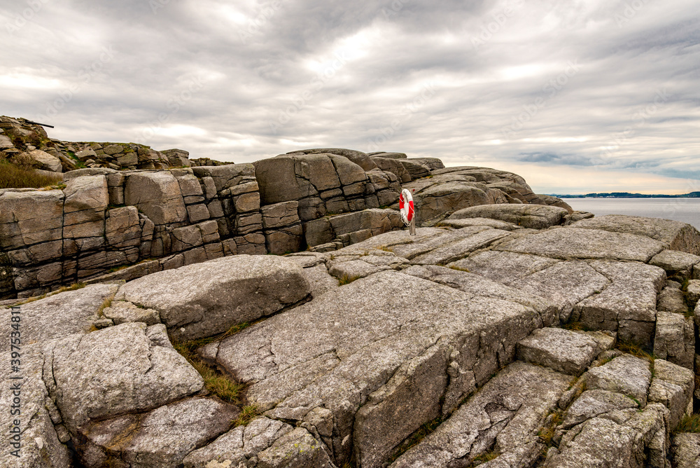 A lifebuoy set at rocky coastline along Fjoloy fort historical site, Rennesoy kommune, Stavanger, Norway, May 2018