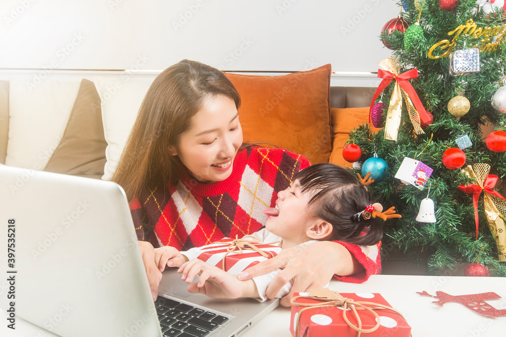 Happy mother and little daughter decorating Christmas tree and gifts at home
