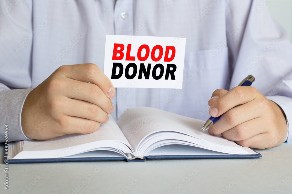 The doctor holds a card with the text BLOOD DONOR. Medical concept The doctor holds a card with the text BLOOD DONOR. Medical concept