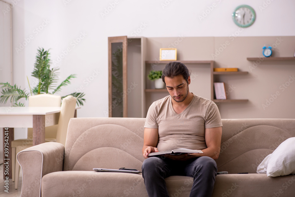 Young male student reading book at home Young male student reading book at home