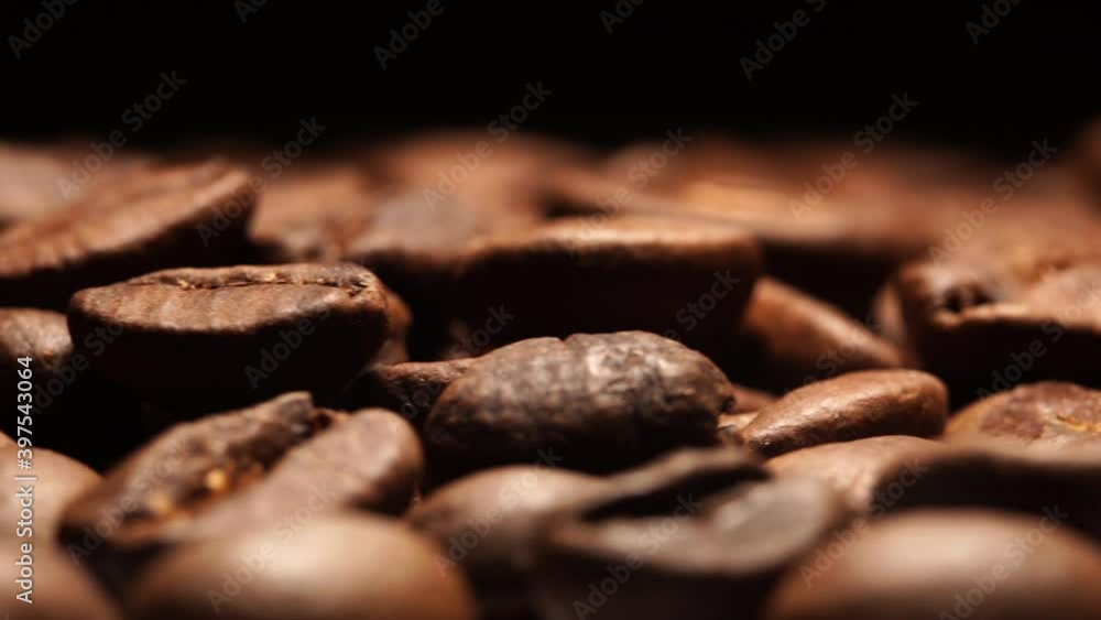 Macro view of fresh coffee beans on black background in rotating motion, extreme close up of roasted coffee beans in rotation. Macro view of fresh coffee beans on black background in rotating motion, extreme close up of roasted coffee beans in rotation.