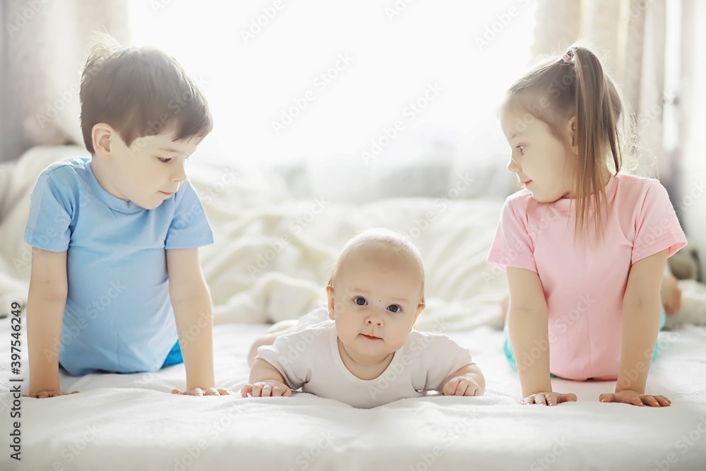 Children lie on the bed next to the newborn baby, little sister. Children lie on the bed next to the newborn baby, little sister.
