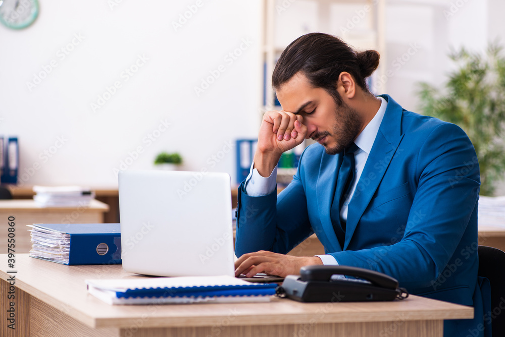 Young businessman employee unhappy with excessive work in the of Young businessman employee unhappy with excessive work in the of