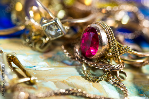 Real gold rings with diamonds, gems, neckless close up macro shot on colorful surface.