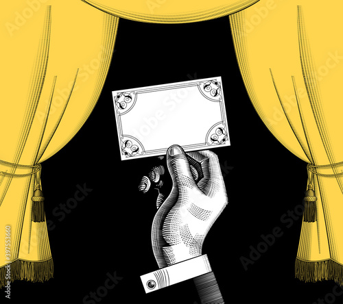 Decorative frame with a yellow curtain in old style and a hand holding a visiting card on black background