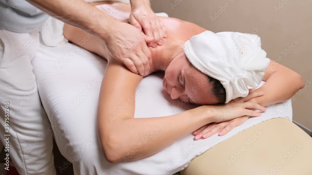 Man therapist doing massage to female patient lying on couch in spa cabinet. Female client getting back massage rejuvenating procedure in beauty clinic. massage of shoulders and neck. Man therapist doing massage to female patient lying on couch in spa cabinet. Female client getting back massage rejuvenating procedure in beauty clinic. massage of shoulders and neck.