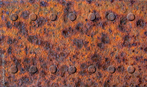 Old rusty stained metal sheet with two rows of rivets close up, metal texture or background 