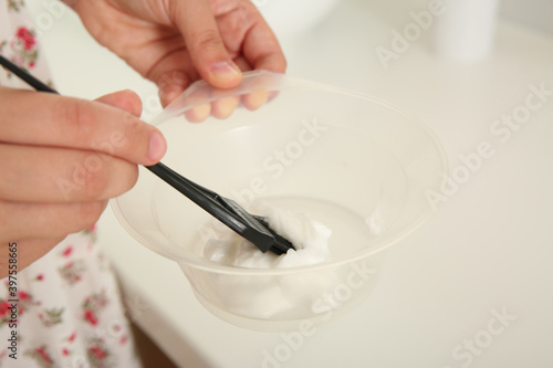 Woman preparing dye for hair coloring in bathroom, closeup