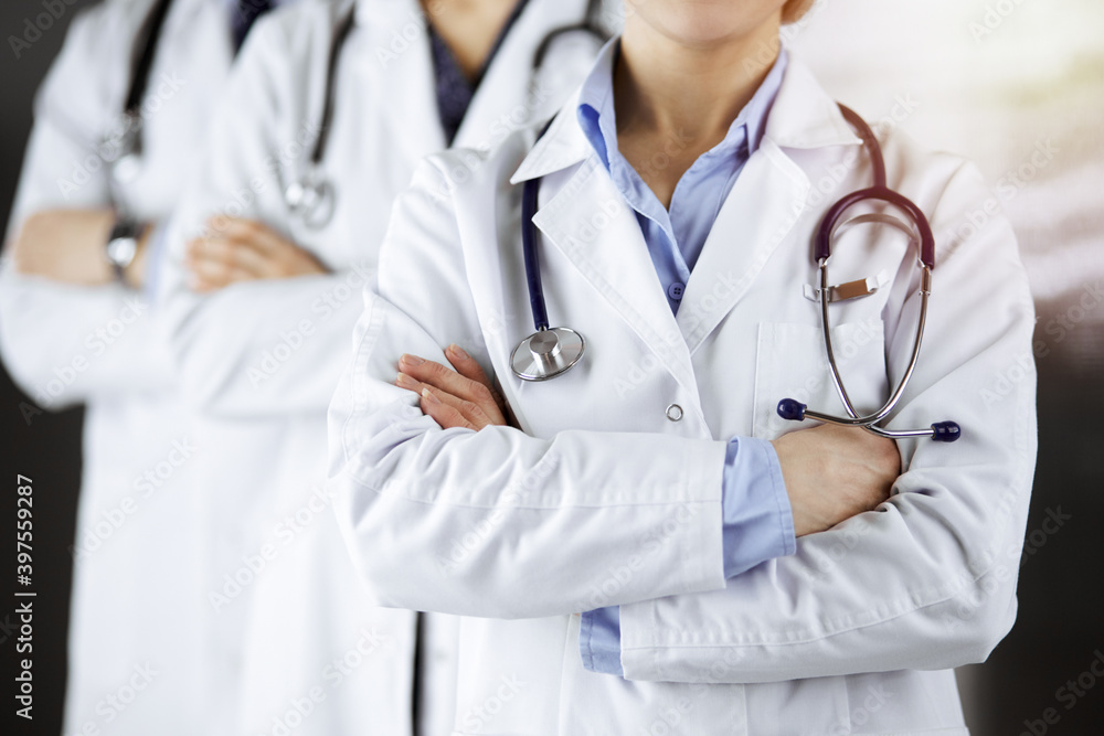 Group of modern doctors standing as a team with arms crossed in sunny hospital and ready to help patients. Medical help, insurance in health care Group of modern doctors standing as a team with arms crossed in sunny hospital and ready to help patients. Medical help, insurance in health care
