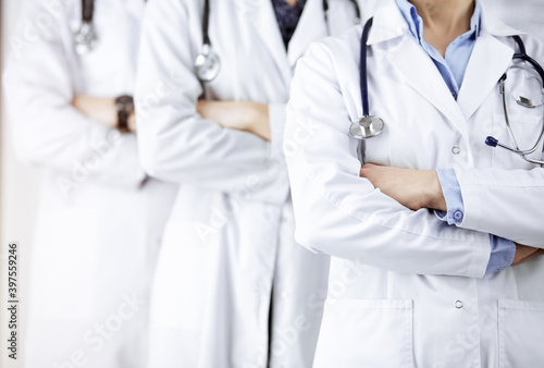Group of modern doctors standing as a team with arms crossed in sunny hospital and ready to help patients. Medical help, insurance in health care