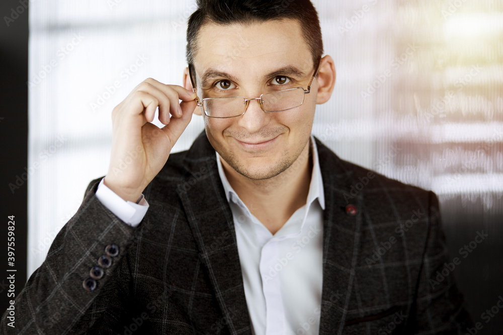 Friendly adult businessman in grey jacket. Business headshot or portrait in sunny office Friendly adult businessman in grey jacket. Business headshot or portrait in sunny office