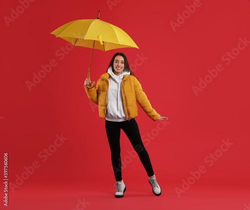 Woman with umbrella caught in gust of wind on red background