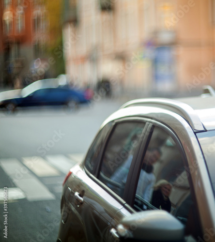Car hood with window and people reflection on blurred street background.