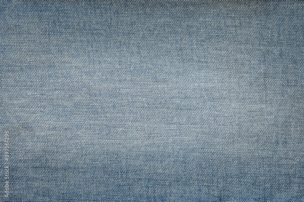 Denim texture. Light denim background with darkened corners and light center. Focusing in the center of the frame. Denim texture. Light denim background with darkened corners and light center. Focusing in the center of the frame.