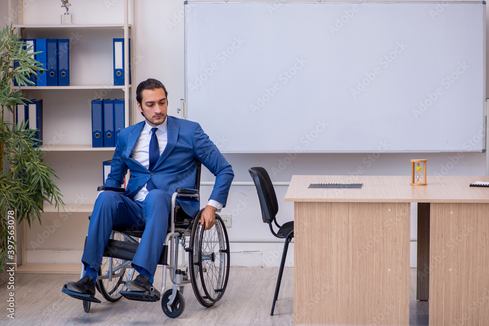 Young male employee in wheel-chair working in the office Young male employee in wheel-chair working in the office