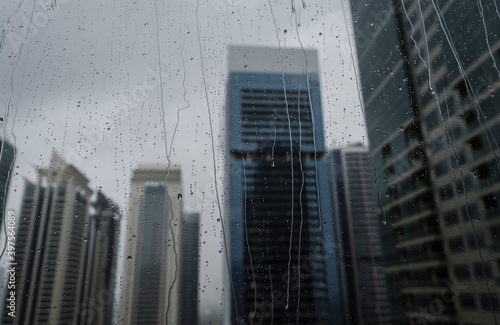 Photography A blur view of office towers through wet window glass pane