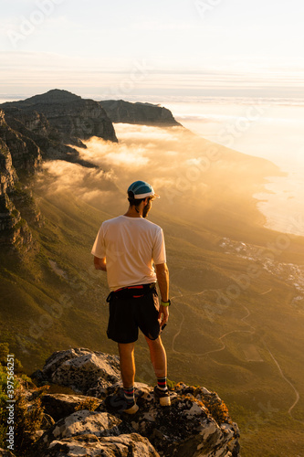 A trail runner enjoying the view of the sunset over the ocean from the top of Table Mountain in Cape Town