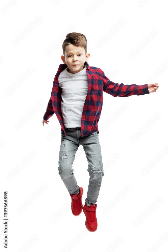 A 7-year-old boy in jeans, a white T-shirt and a red shirt is jumping. Isolated on white background. Vertical. A 7-year-old boy in jeans, a white T-shirt and a red shirt is jumping. Isolated on white background. Vertical.