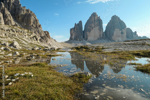 A panoramic view on the famous Tre Cime di Lavaredo  Drei Zinnen   mountains in Italian Dolomites. The mountains are reflecting in small paddle. Desolated and raw landscape. Natural phenomenon