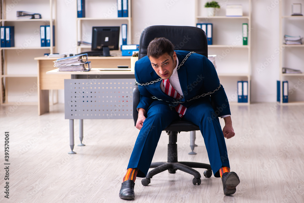 Chained male employee working in the office Chained male employee working in the office