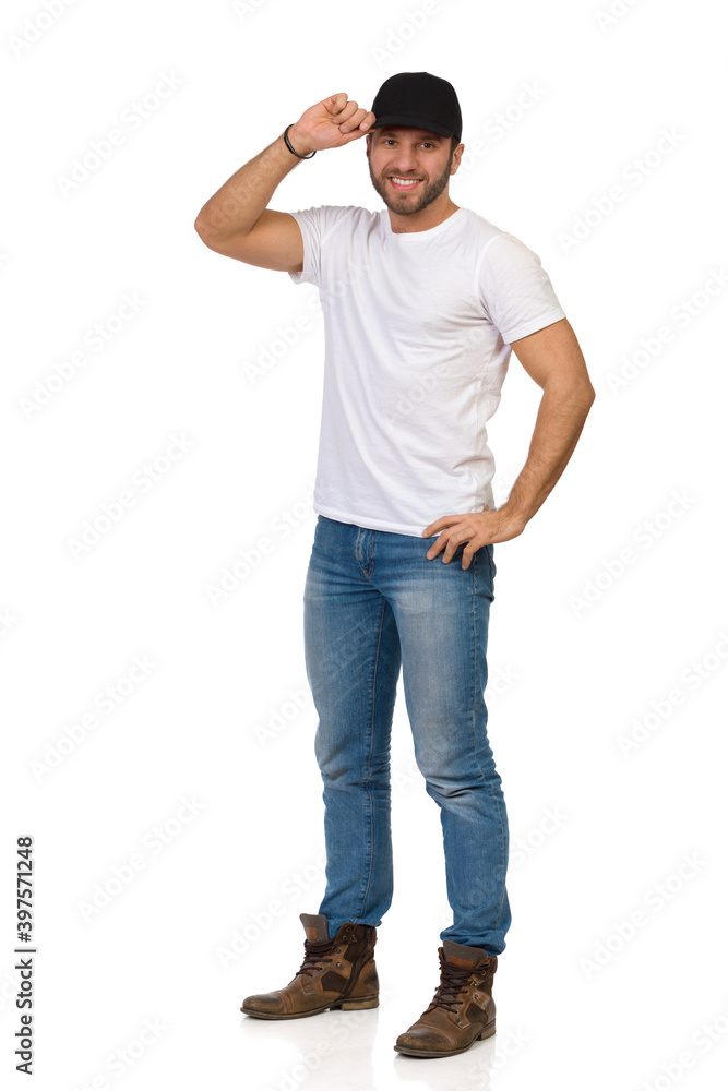 Fototapeta premium Smiling Young Man In Jeans, White T-shirt Is Standing And Posing In Black Cap