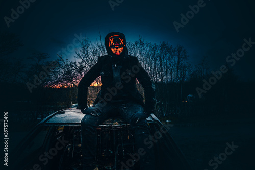 Purge mask, halloween with pumpkin. LED mask, creepy scary man. Corona, Funny, October, outside. Urban scene car photo