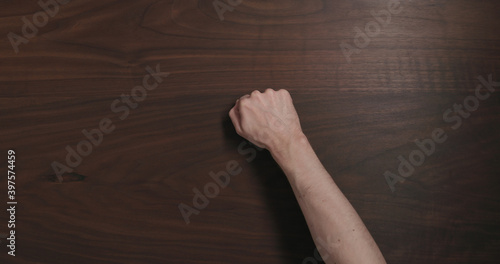 Obraz na płótnie Top view man hand knock on black walnut table with copy space
