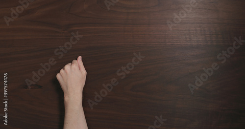 Top view man hand knock on black walnut table with copy space