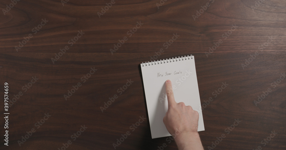 Obraz premium Top view man show notepad with new year goals on walnut wood table