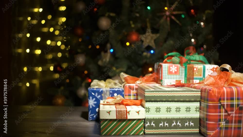 Beautiful Christmas gifts on a table at home and tree with lights in the background, festivity and holiday concept Beautiful Christmas gifts on a table at home and tree with lights in the background, festivity and holiday concept
