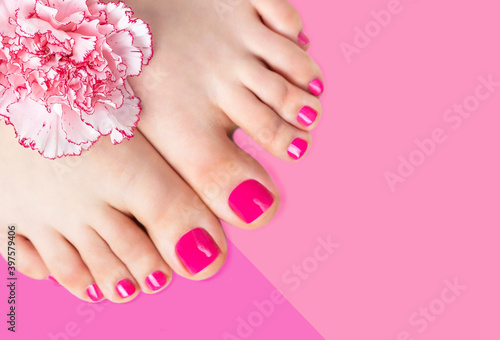 Pedicure with a flower on pink background, copy space